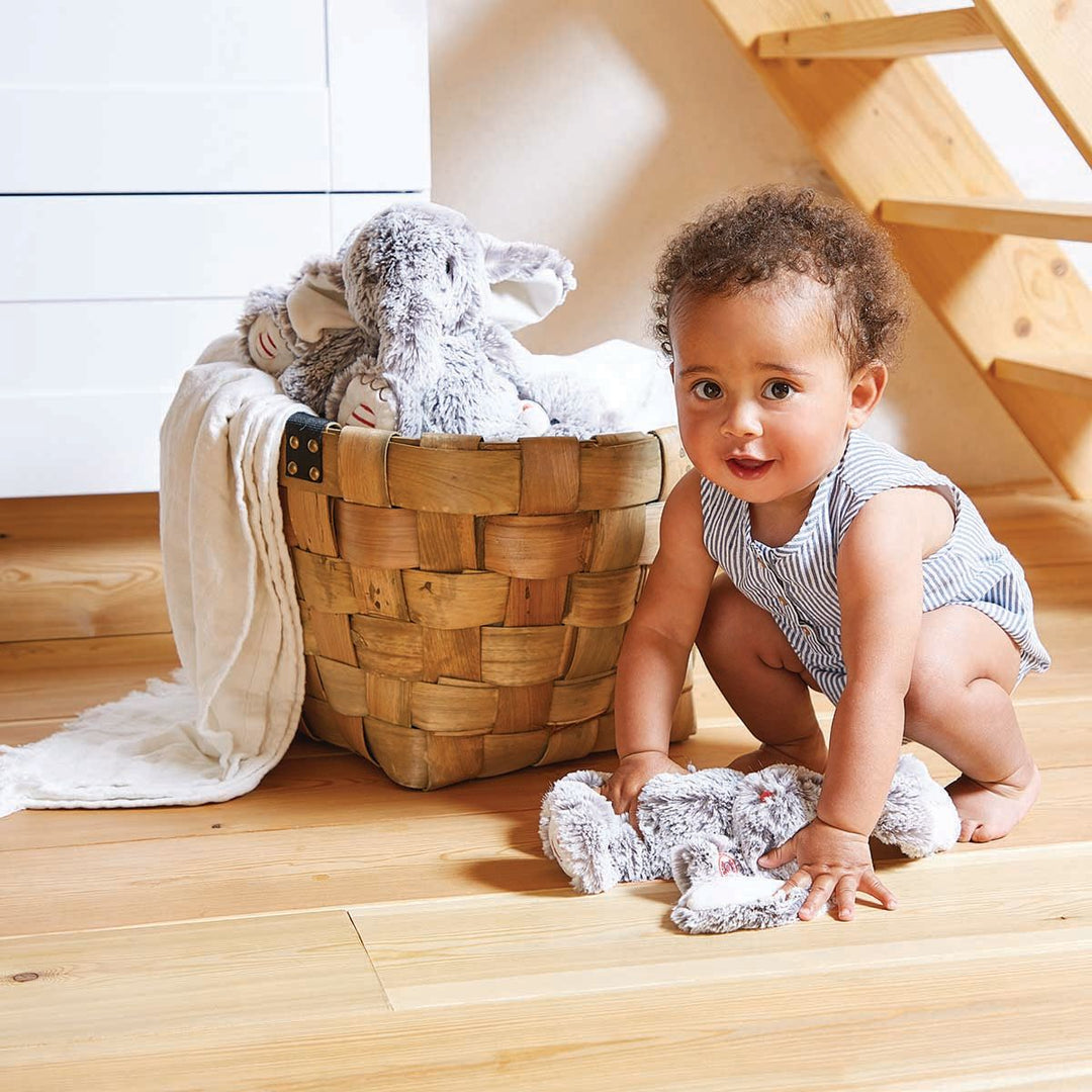 Baby next to a basket filled with soft toys