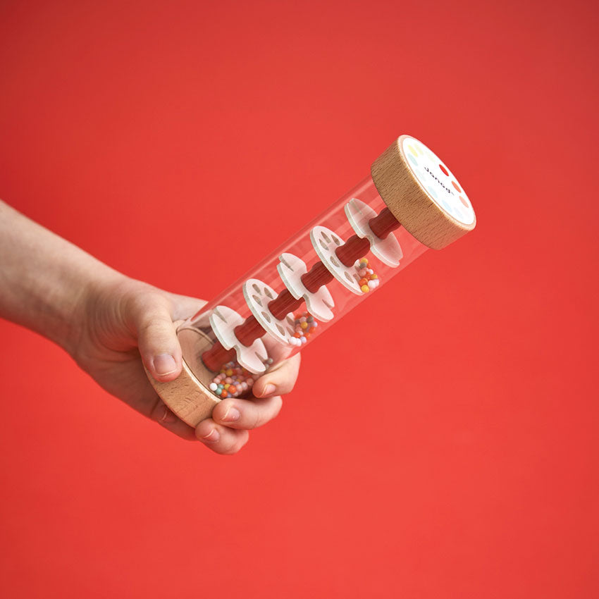 Hand holding a cylindrical wooden puzzle against a red background
