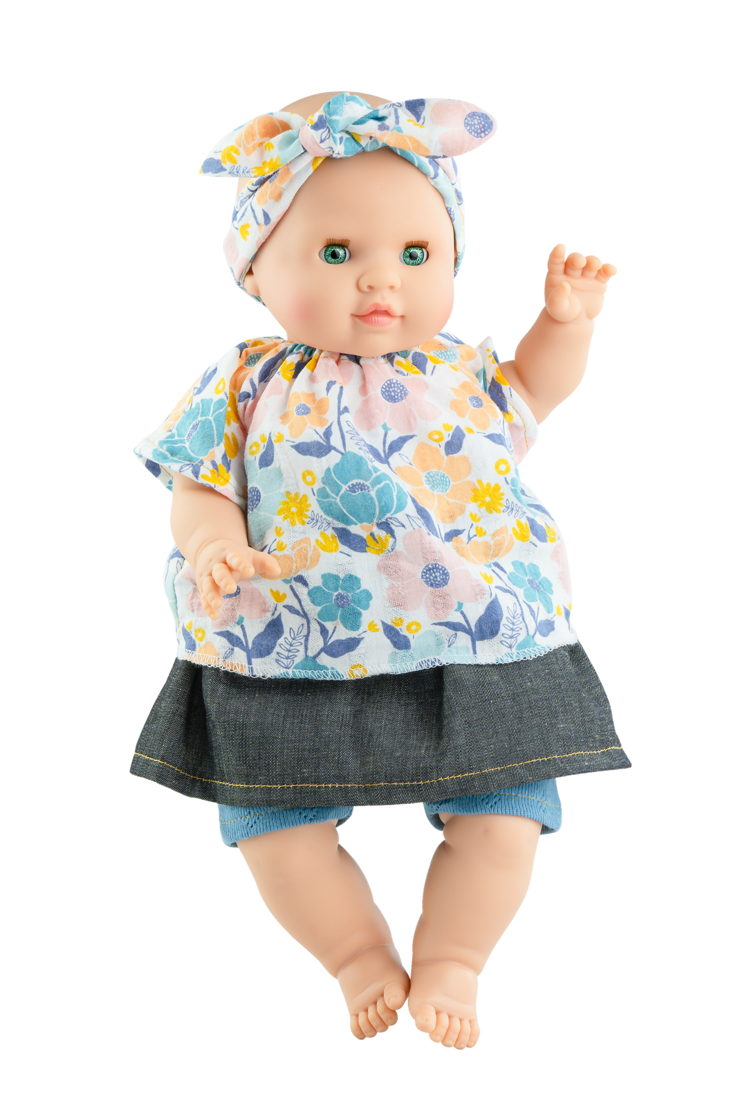 A soft body doll with a vinyl head and limbs, dressed in a floral skirt and a patterned top, with a bow on the head.