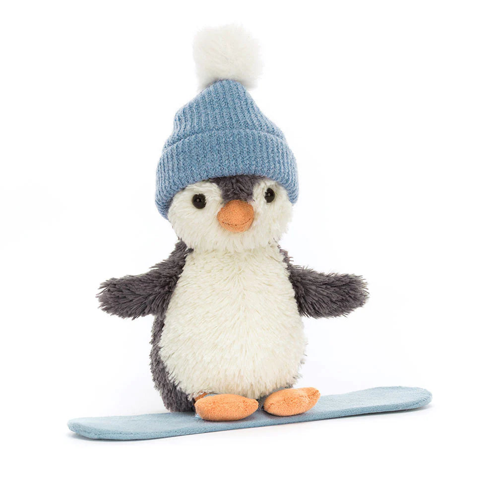 Black and white penguin sot toy, wearing blue beanie with white pompom, standing on a blue snowboard