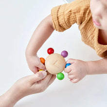 Child playing with a colorful wooden toy held by an adult on a white background