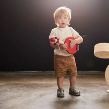 Child holding a toy guitar in a dark room with a spotlight effect