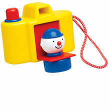 A colorful toy camera with a clown figure inside, featuring a red shutter button and a blue viewfinder.