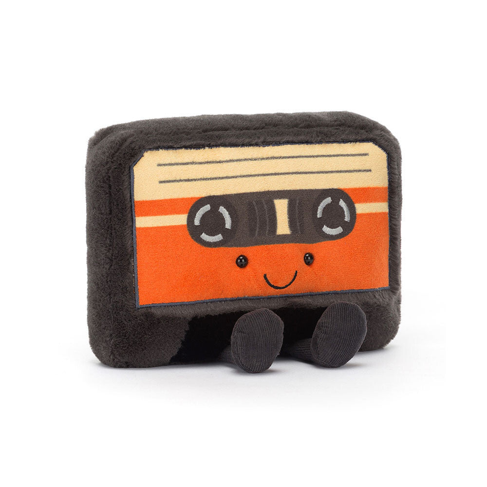 A plush toy designed to look like a retro cassette tape with a smiling face, silver embroidered reels, and orange and butterscotch colored details.