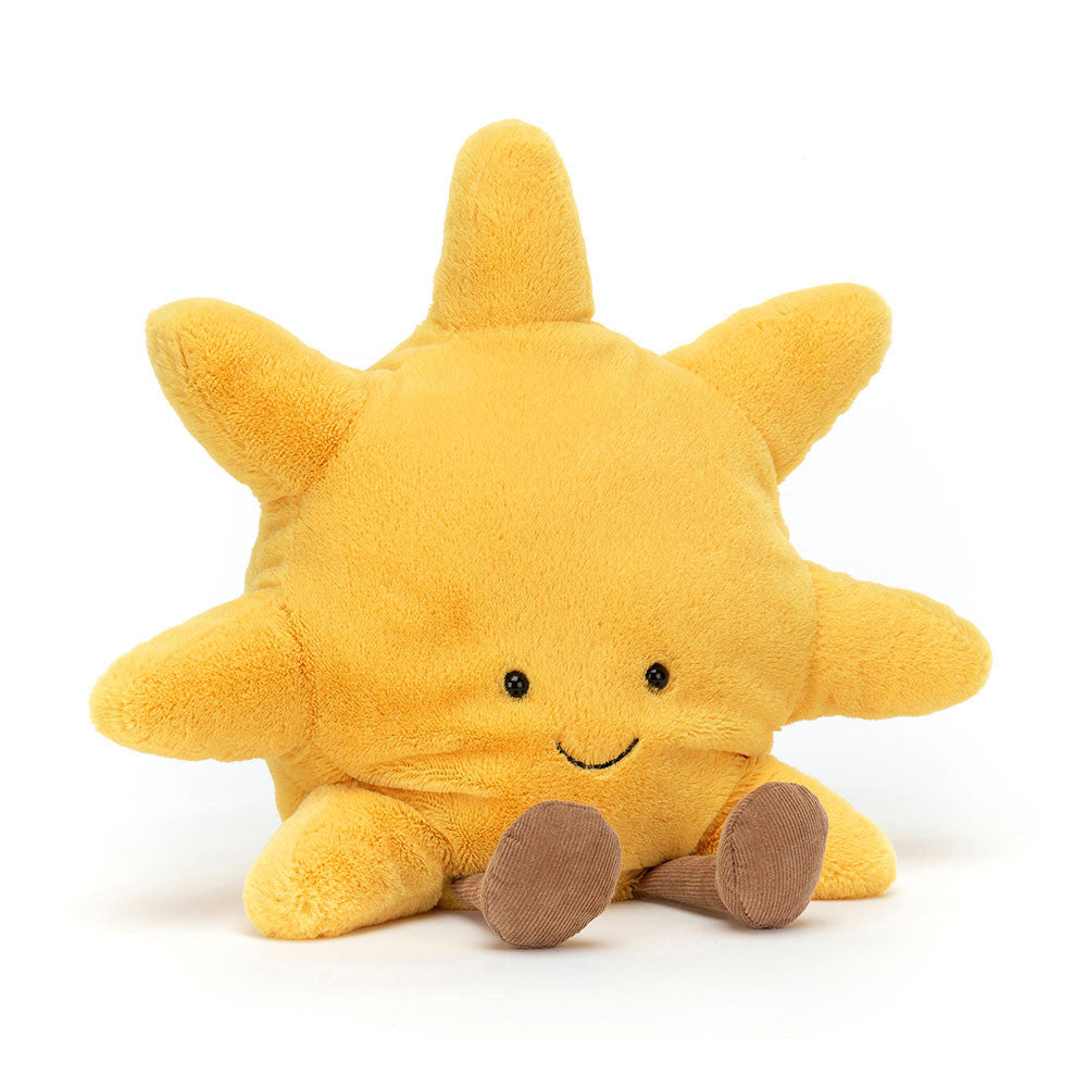 A plush toy in the shape of a sun with a smiling face and brown feet.