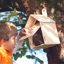 Child interacting with a birdhouse attached to a tree