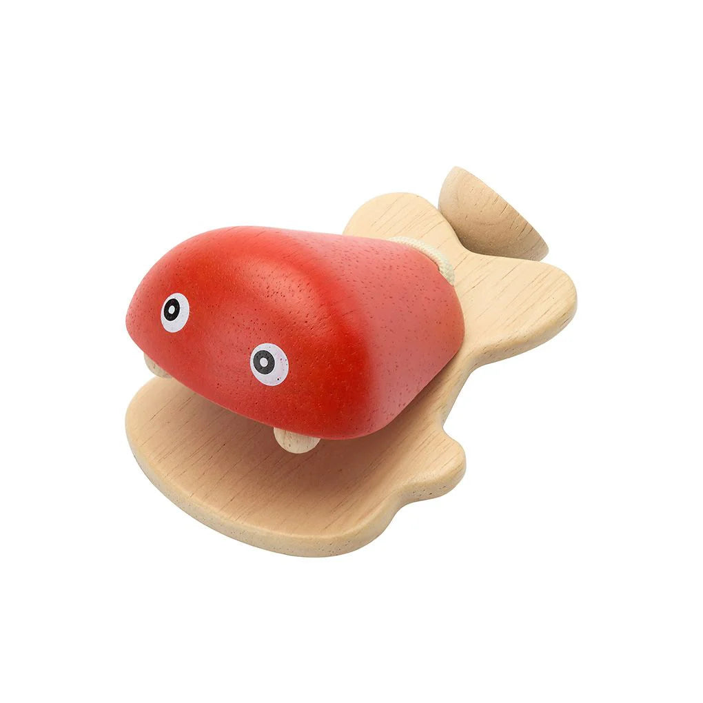 Wooden toy fish castanet with red body and black and white eyes on a white background