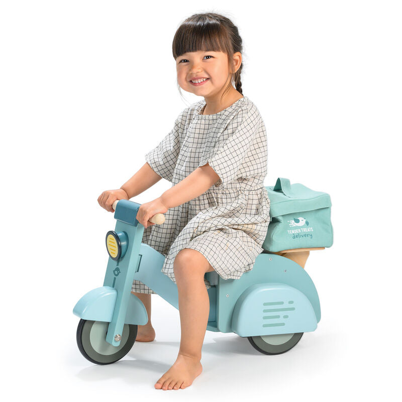 Child sitting on a light blue toy motorcycle with a white background