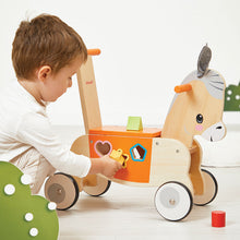 Child playing with a wooden toy donkey on a light wooden floor.