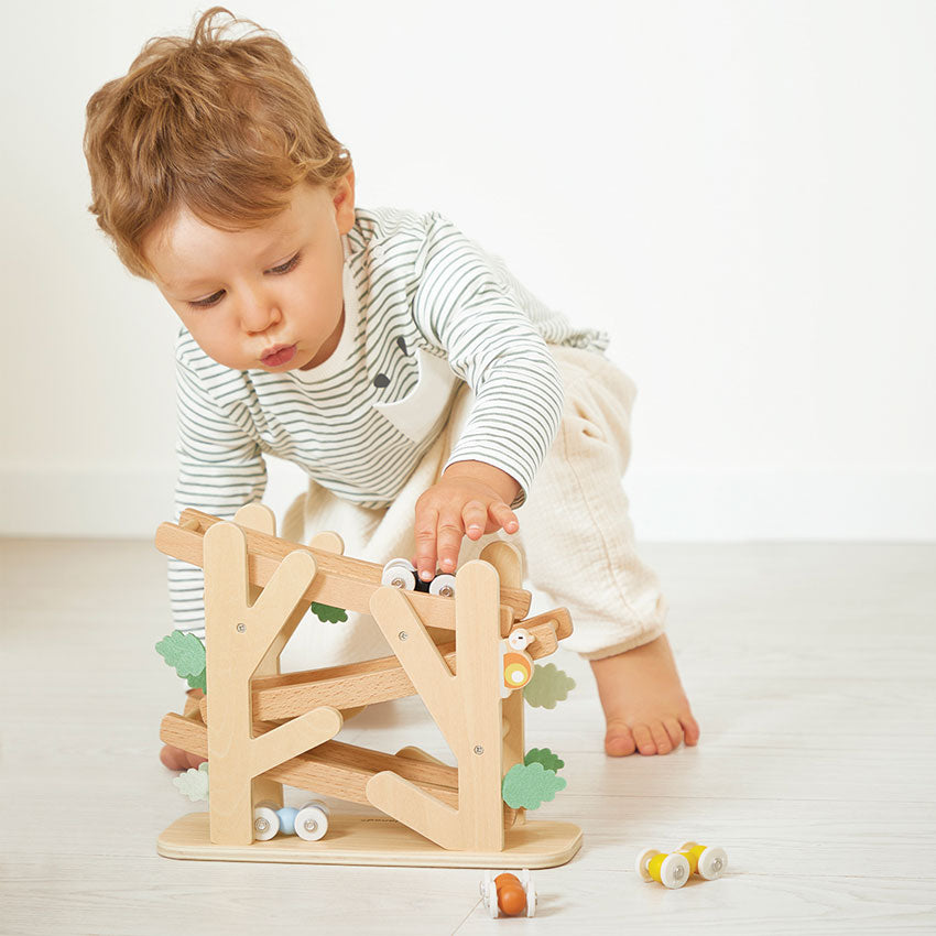 Child playing with a wooden toy on a light wooden floor.