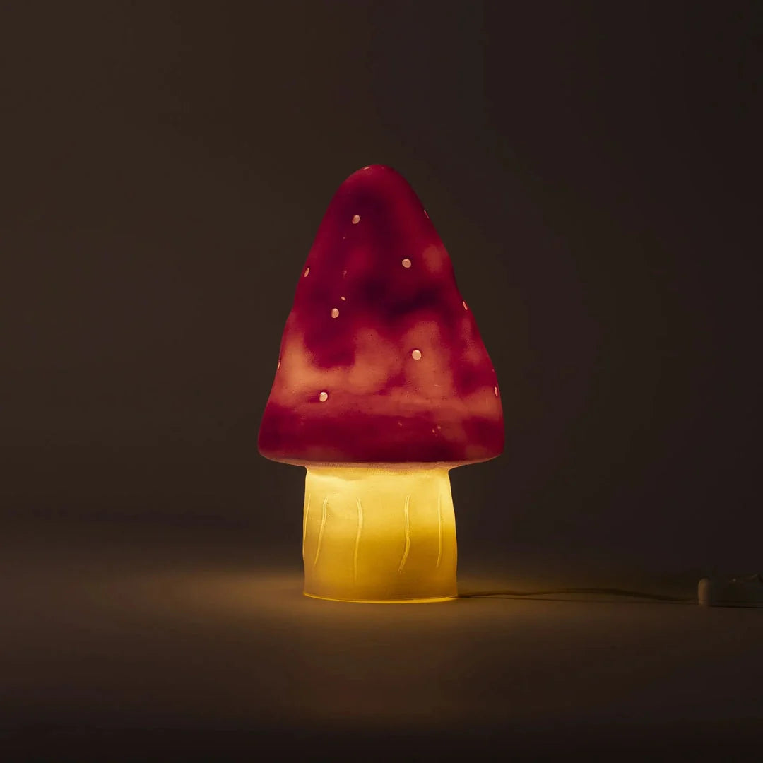 Mushroom-shaped lamp with pink cap and yellow base on a dark background