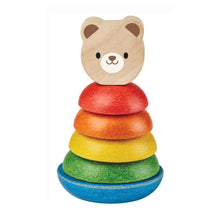 A wooden stacking toy consisting of colorful rings and a bear-shaped piece, arranged in a tower with the bear on top.