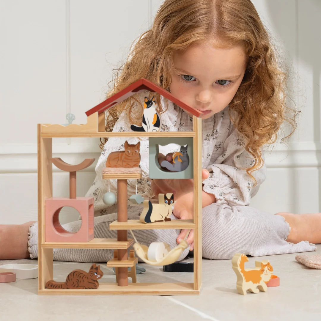 Child playing with a wooden animal playset on a light-colored floor.
