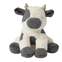 A plush toy resembling a cow with a primarily white body and grey spots, round black eyes, and a smiling expression. The toy has grey ears, a black nose, and grey feet.