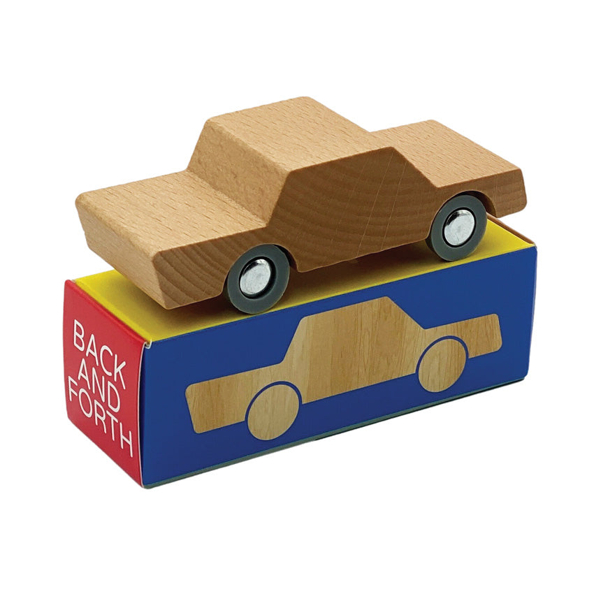 A wooden toy car with a neutral color placed on a box with the text 'BACK & FORTH' printed on it.