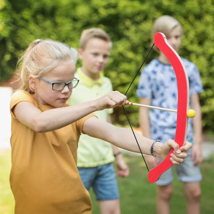 Girl with glasses using a red bow and arrow outdoors