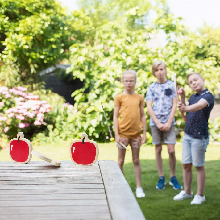 Children playing with red apple-shaped toys outdoors in a garden.