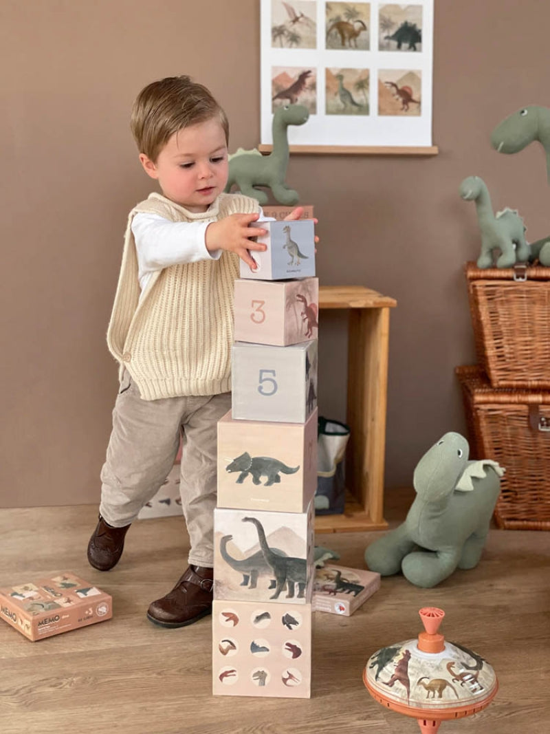 Child playing with dinosaur-themed blocks in a room with toy storage and decor.