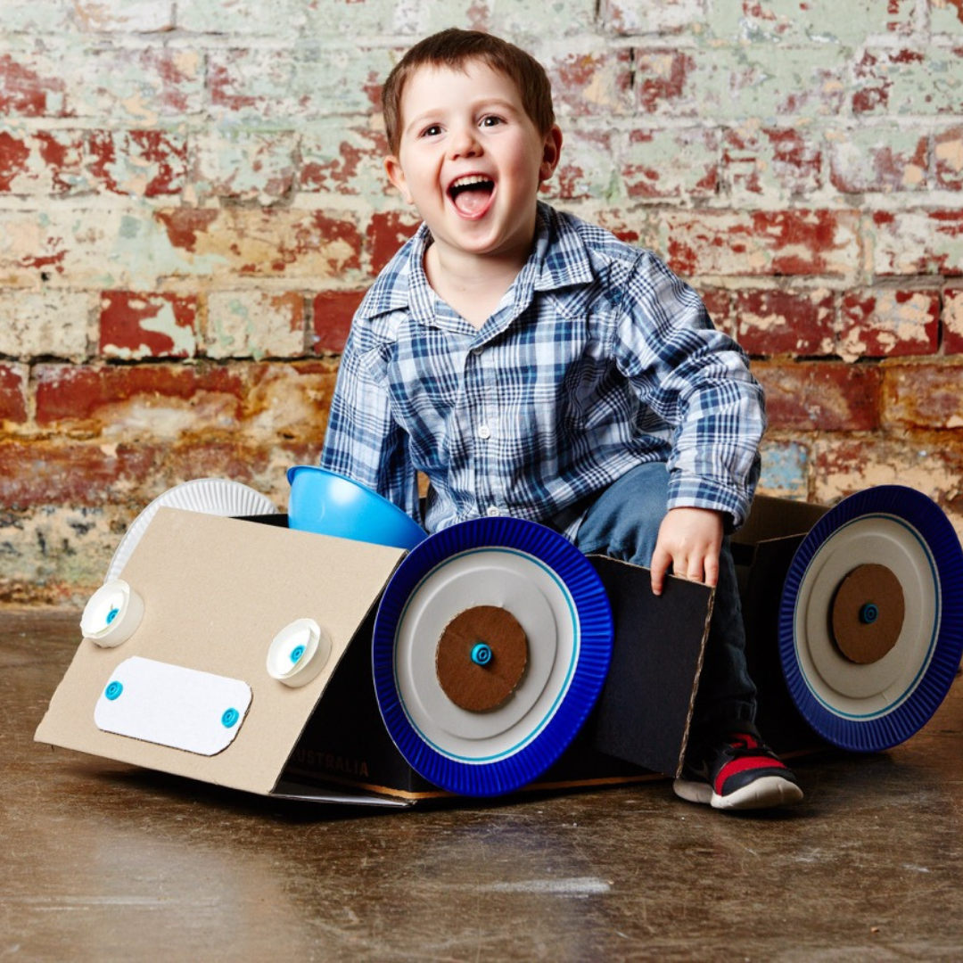 Child sitting in cardboard handmade car