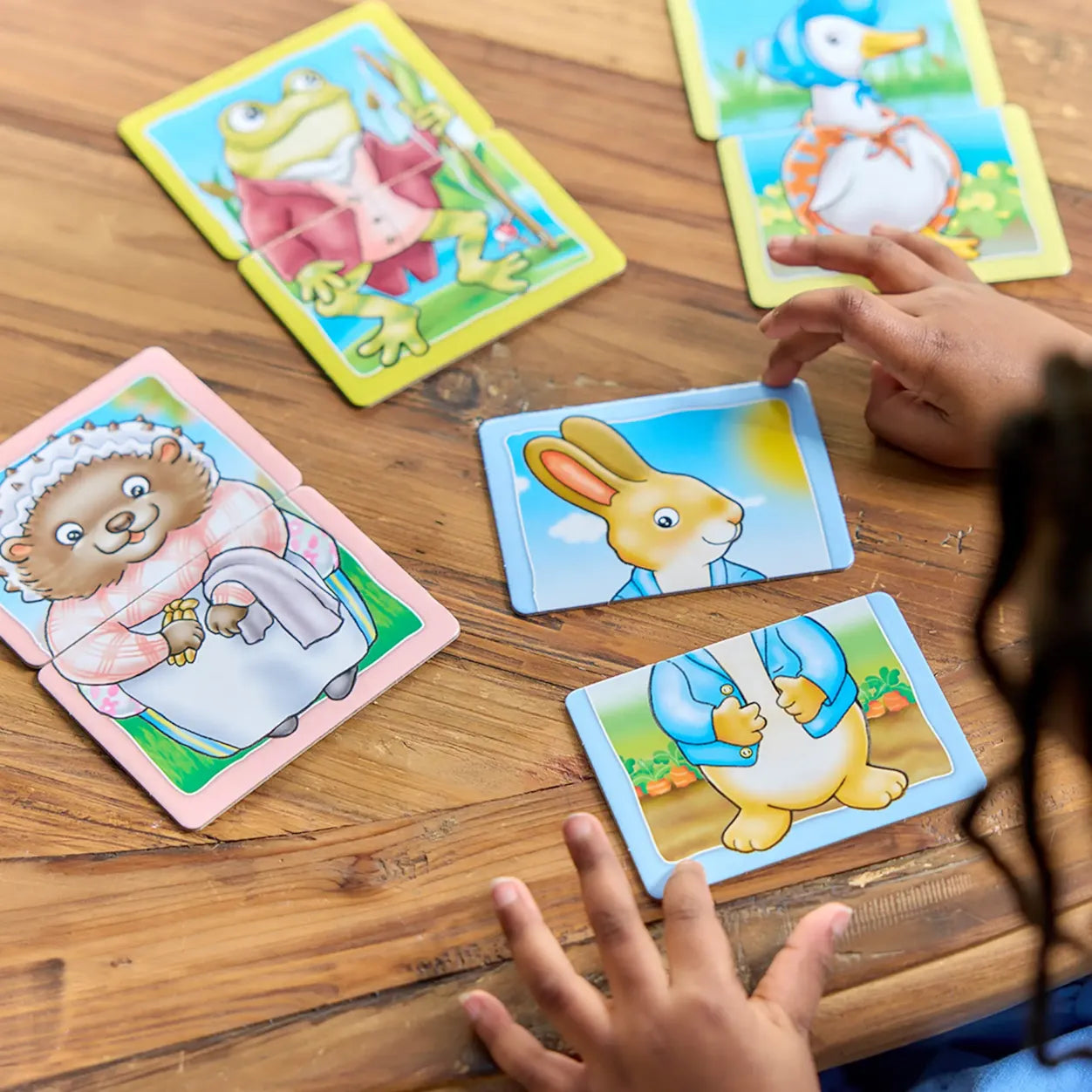 Children playing with animal-themed cards on a wooden table