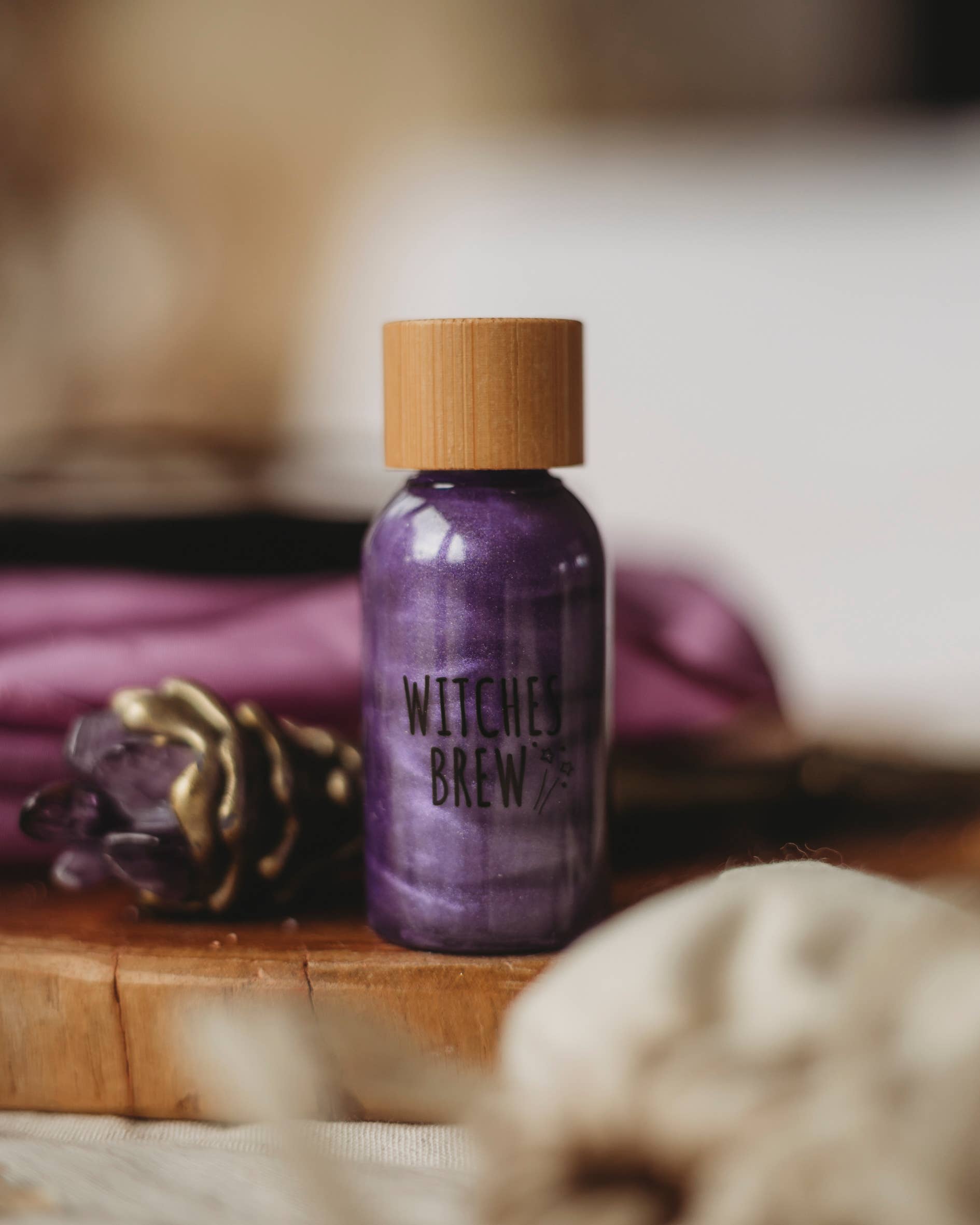 Purple bottle labeled 'Witches Brew' on a wooden surface with blurred background