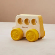 A wooden push toy resembling a bus with yellow wheels and a beige body, made by PlanToys.
