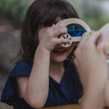 Young girl in blue dress playing with blue Wautmobile car toy from PlanToys