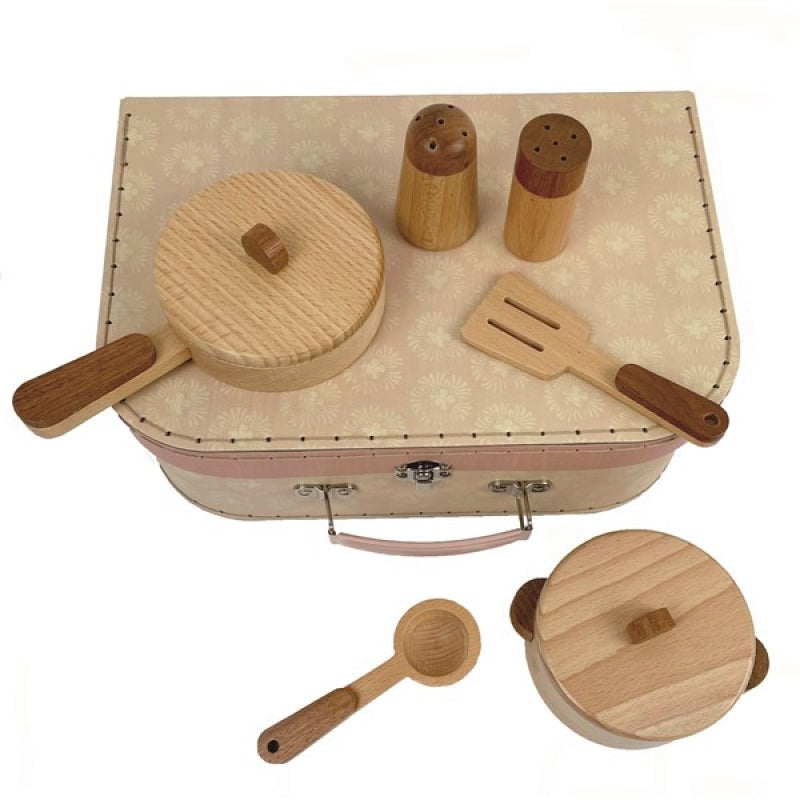 wooden toy cooking utensils sitting on a cardboard suitcase on a white background