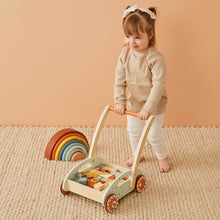 Young girl pushing wooden cart on a plush cream carpet
