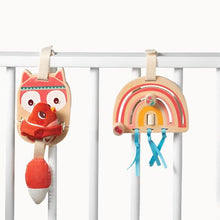 Fox and rainbow baby activity toys made of wood and other assorted materials, attached to white wooden bars resembling the side of a babies cot.
