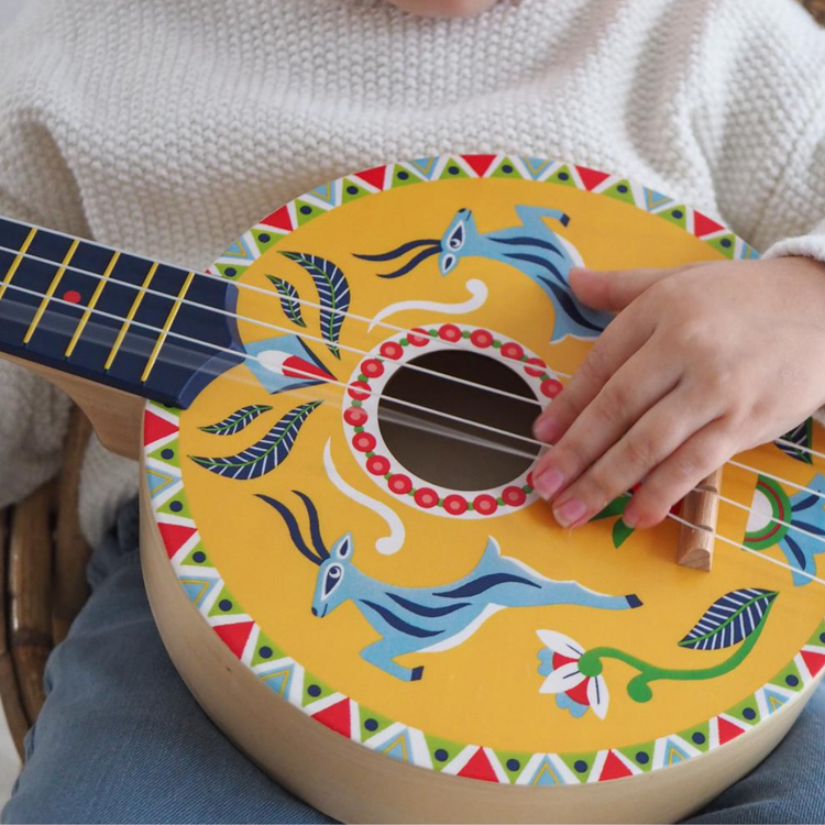 Childs hand holding a yellow painted wooden guitar toy