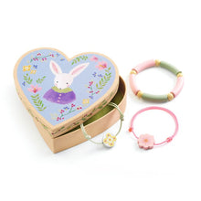 Heart-shaped jewelry box with rabbit design and two colorful bracelets on a white background