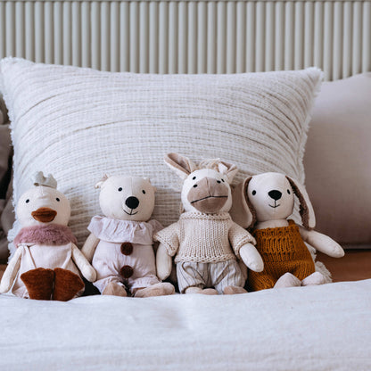Four plush toys on a bed with a textured pillow in the background