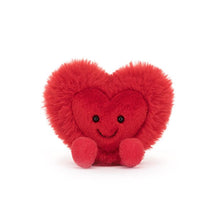 A bright red plush toy in the shape of a heart with a fluffy mane and a stitched smile.