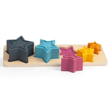 A set of colorful silicone stars in various sizes, along with a wooden sorting board, designed for young children as a shape sorting and stacking toy.