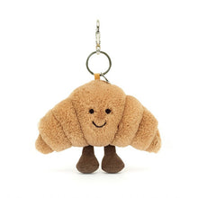 Plush croissant shaped keychain with a smiling face on a white background