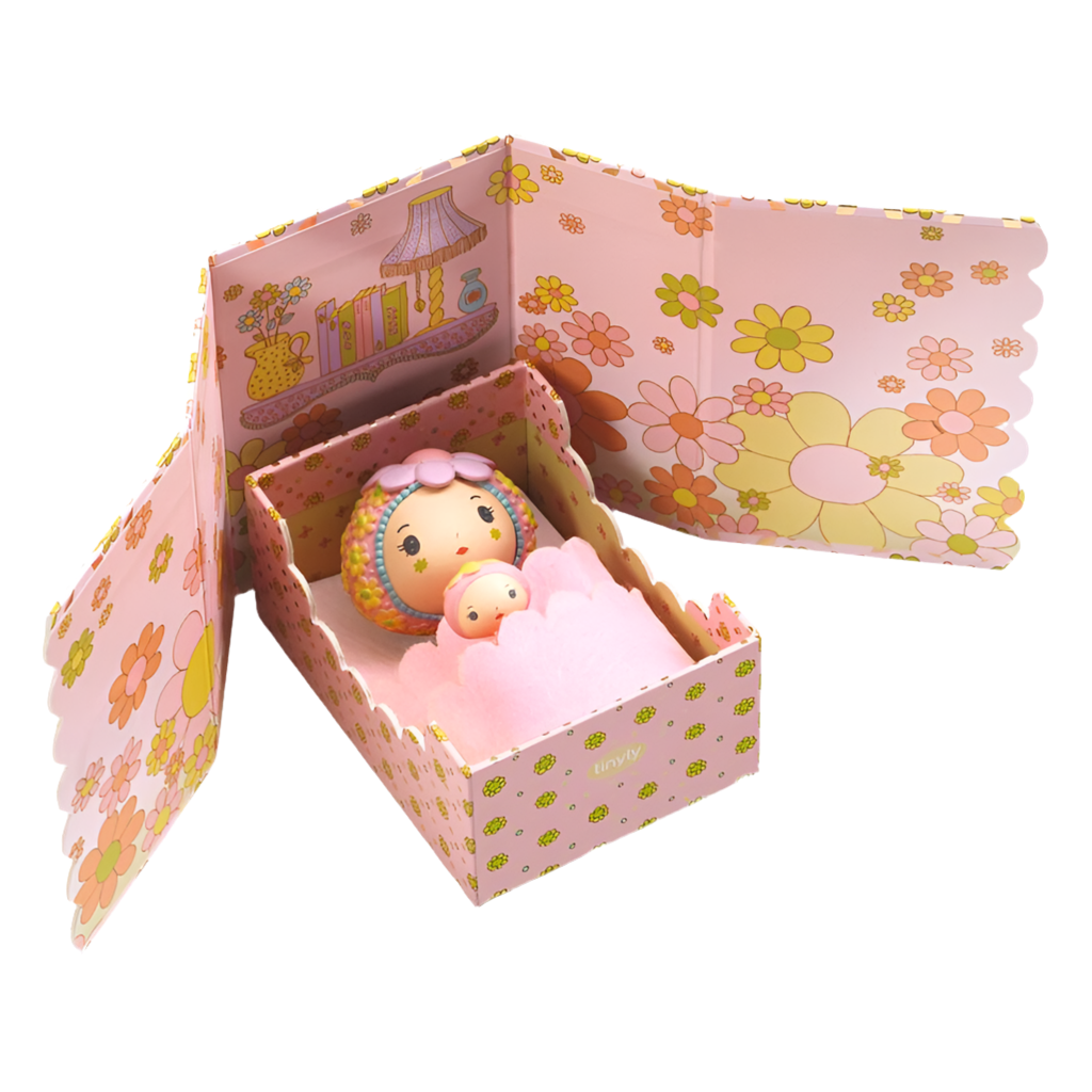 A miniature doll set called 'Rose Tiny Room' with a pink-colored box that opens to reveal a small pink doll and accessories like a bed and a felt cover.
