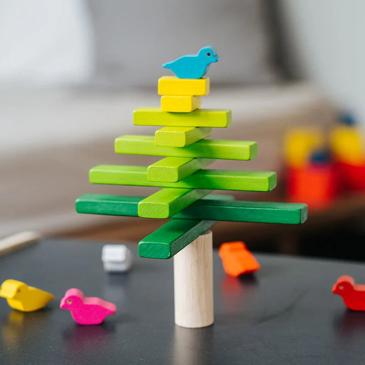 Colorful wooden block toy shaped like a tree with birds on a blurred background