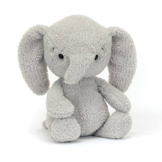 A plush toy resembling a gray elephant with a curved trunk and cuddly features, seated with a sweet expression.