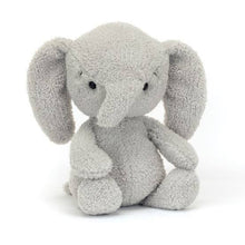 A plush toy resembling a gray elephant with a curved trunk and cuddly features, seated with a sweet expression.