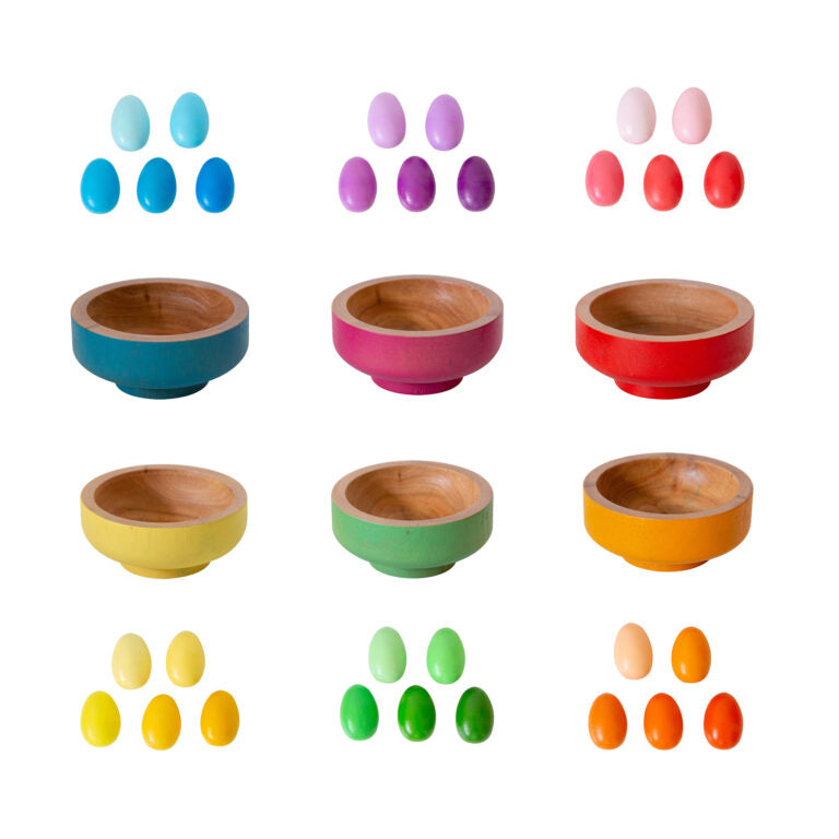 Assorted colourful small wooden eggs and matching wooden bowls displayed on a plain white background.