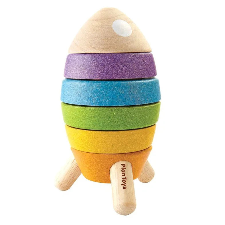 A colorful stacking rocket shape sorter with rings in blue, green, yellow, and purple, mounted on a wooden base with a white astronaut figure on top.