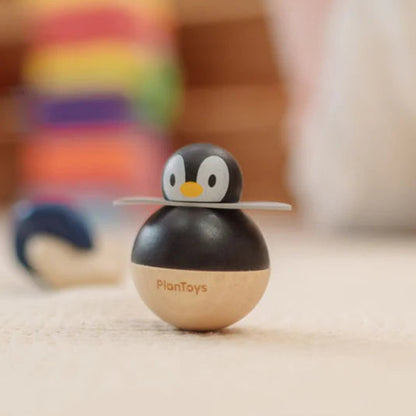 Wooden penguin toy with 'PlanToys' branding on a wooden surface.
