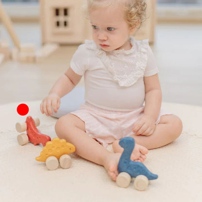 Child playing with wooden toys on a light-colored floor.