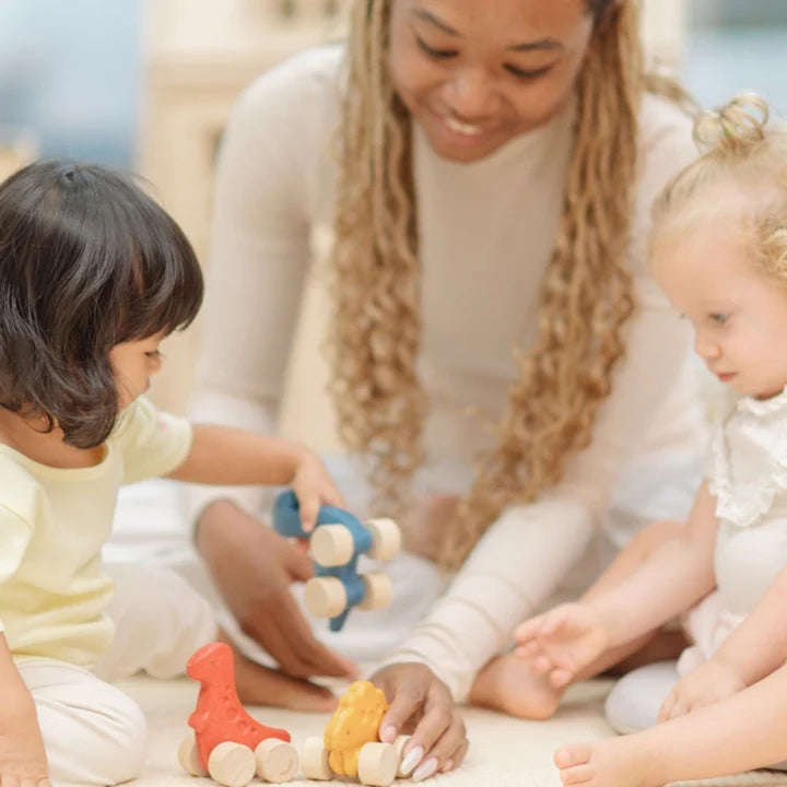 Woman sitting on the floor with two children playing with toys.