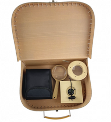 Open brown cardboard case with black pouch, wooden magnifier, and circular object on a white background