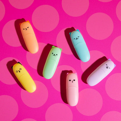 Colorful highlighter markers with cartoon kitten faces on a pink polka dot background