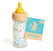 A pretend play feeding bottle with a wooden cap and a design that resembles a rabbit, accompanied by a product tag indicating the brand Pomea.