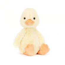 A plush toy resembling a duckling with cream-colored fur, orange beak and feet, and a perky tail.