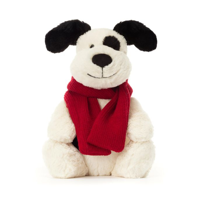 A plush toy resembling a black and cream colored puppy with a red scarf.